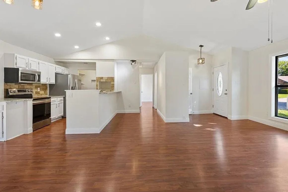 Light, airy kitchen with white cabinets, granite countertops, bronze fixtures, a spacious island, and ample natural light