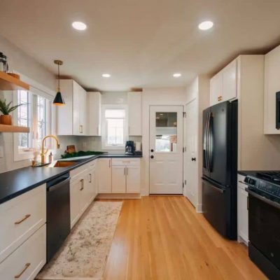 Bright Flower Mound, TX kitchen featuring white cabinets, dark countertops, stainless appliances, floating shelves, and hardwood floors